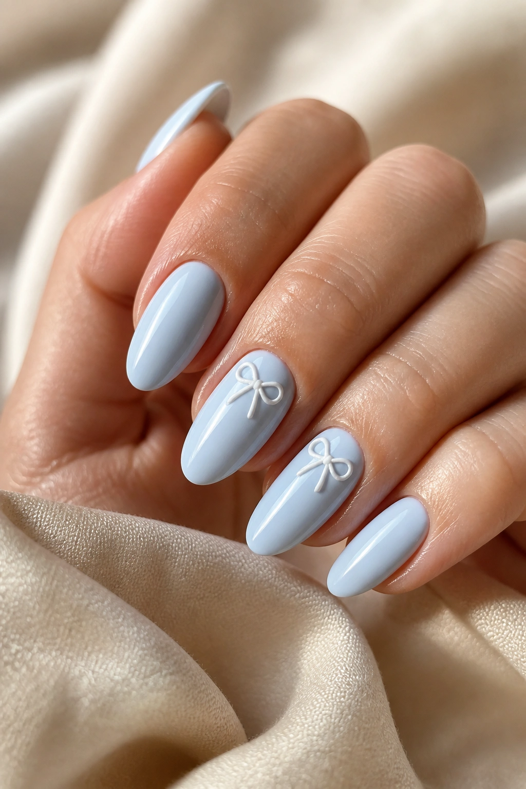 Real hand with pastel blue almond nails featuring tiny painted bows