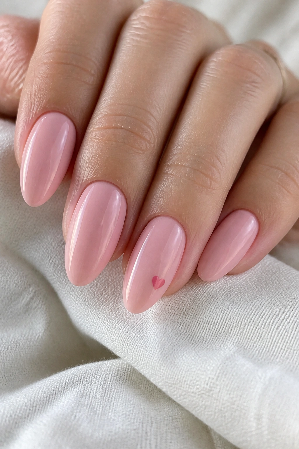 Almond nails with tiny heart accent on ring finger