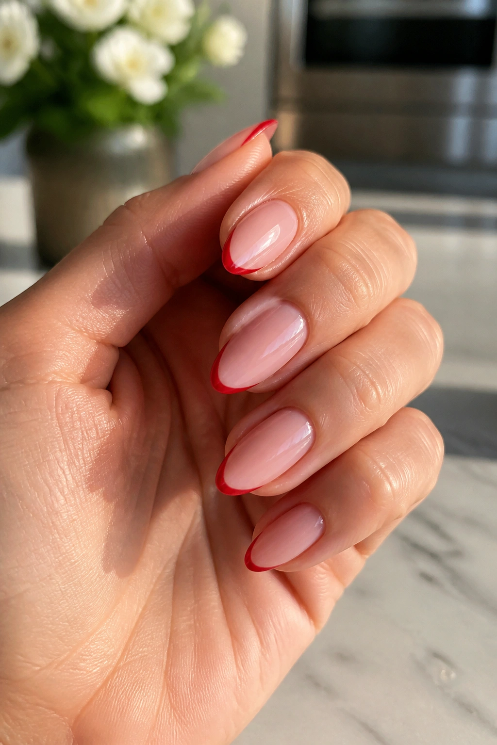 Close-up of tomato red micro-French almonds nails on a real hand.