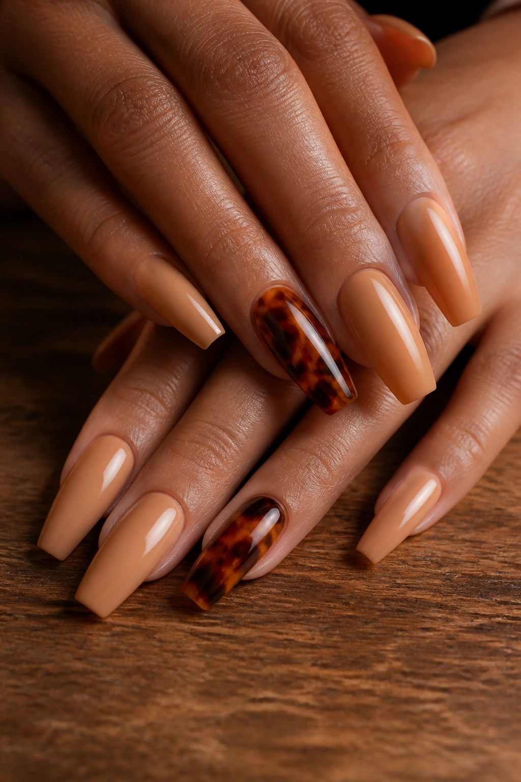 Close-up of hands with tortoiseshell accent coffin nails on warm background