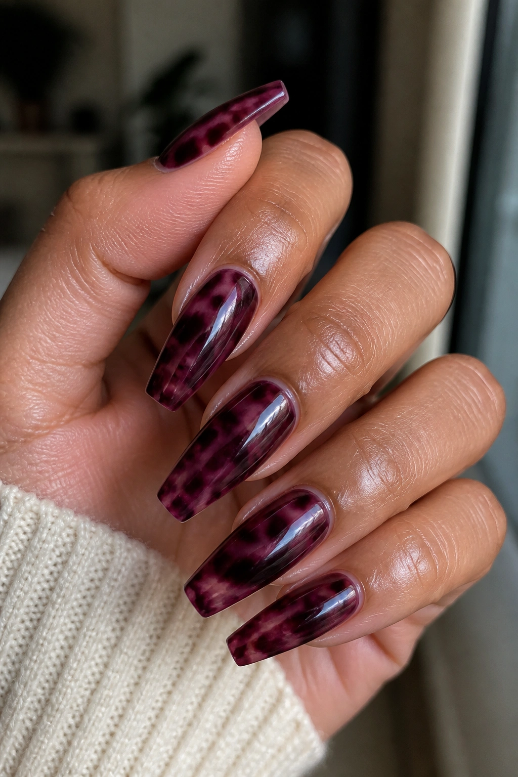 Close-up of burgundy-purple tortoiseshell coffin nails