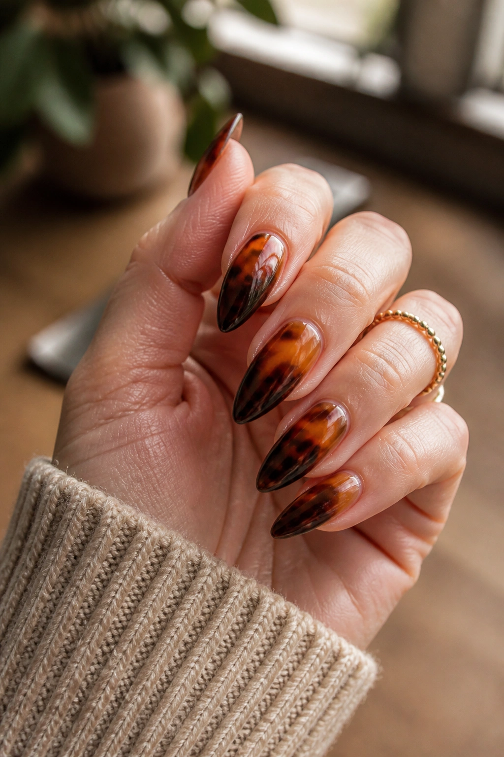 Close-up of tortoiseshell ombre almond nails on a real hand with amber-brown tones