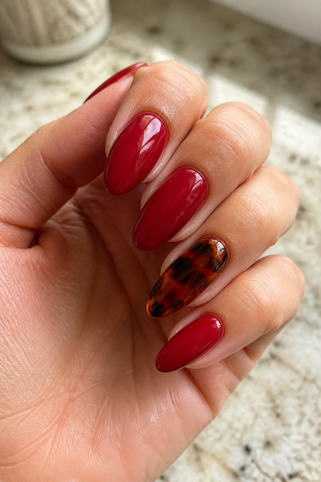 Close-up of red tortoiseshell accent nail on almond nails