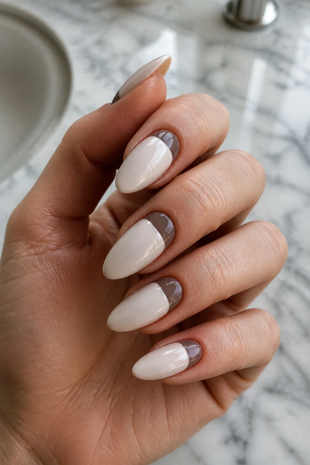 Close-up of two-tone almond nails with a curved half-moon near the cuticle.