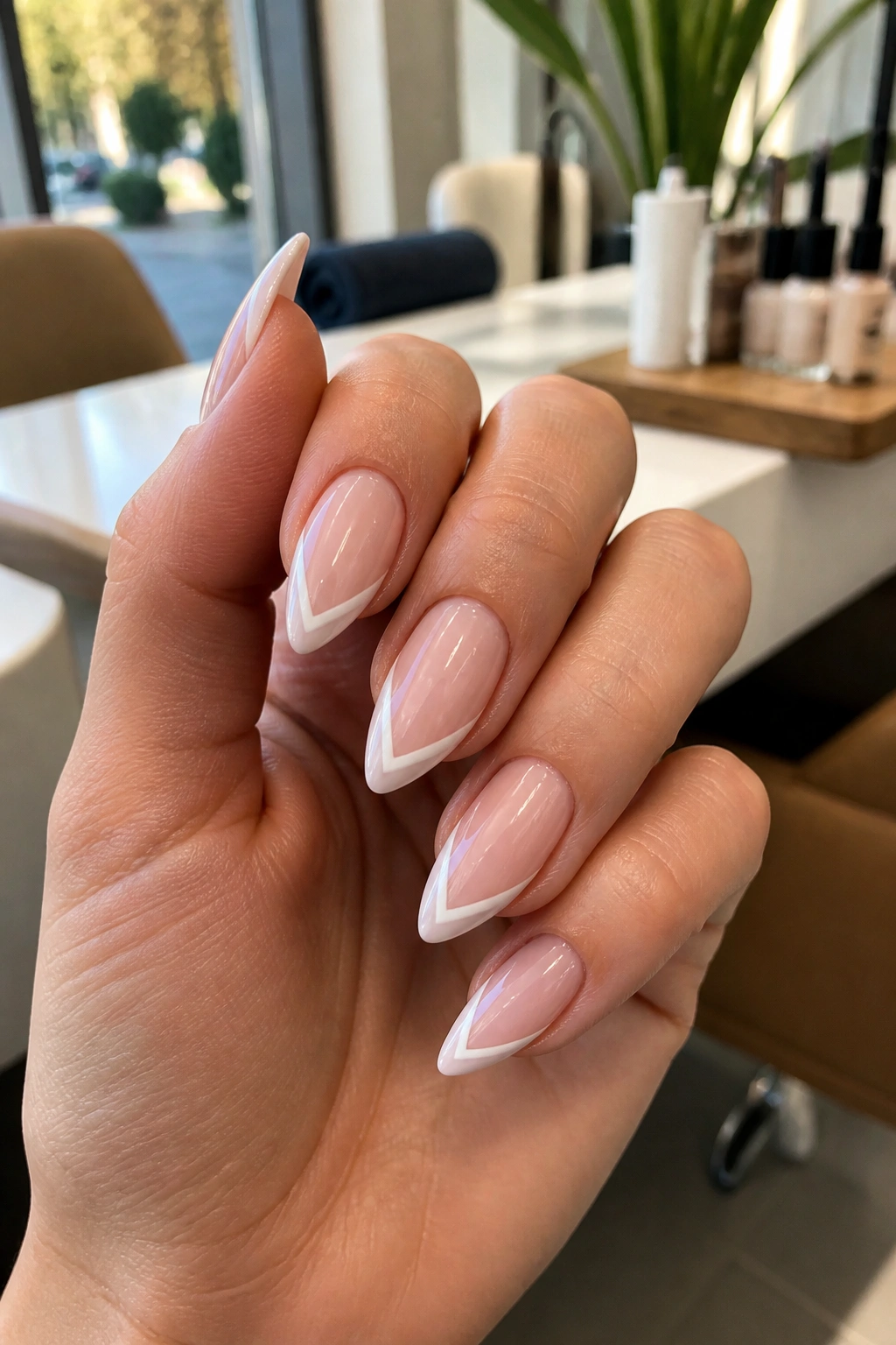 Close-up of almond nails with a V-shaped white tip and negative space on nude base