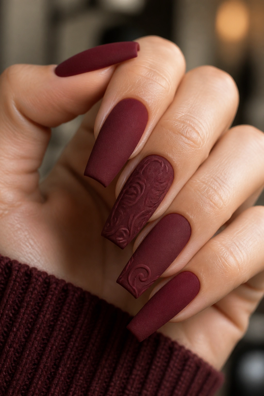Close-up of velvet burgundy matte nails with subtle swirls