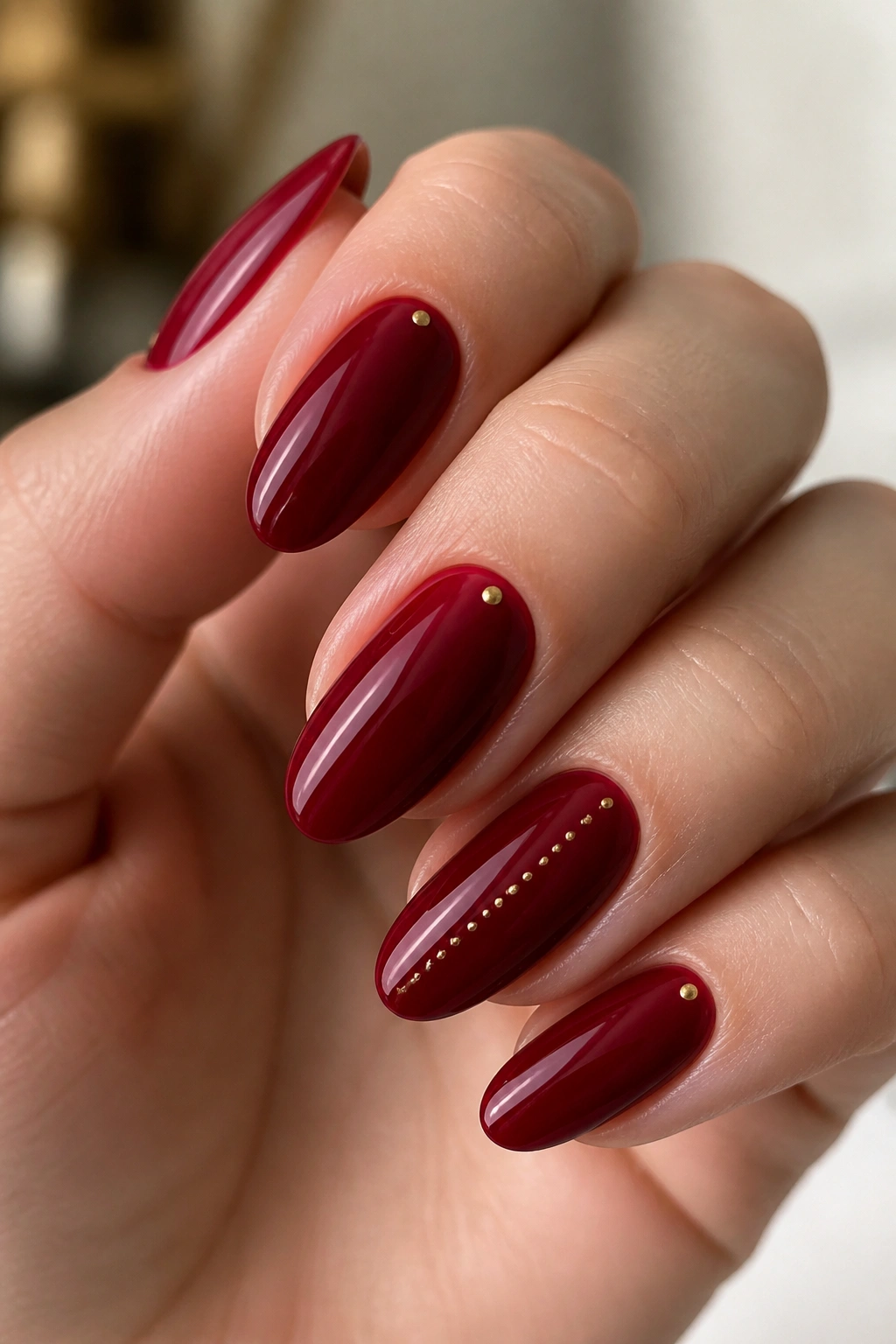 Almond nails venetian red with tiny dots on a real hand