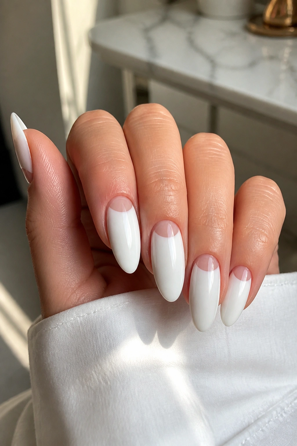 Close-up of white almond nails with negative space design on a real hand.