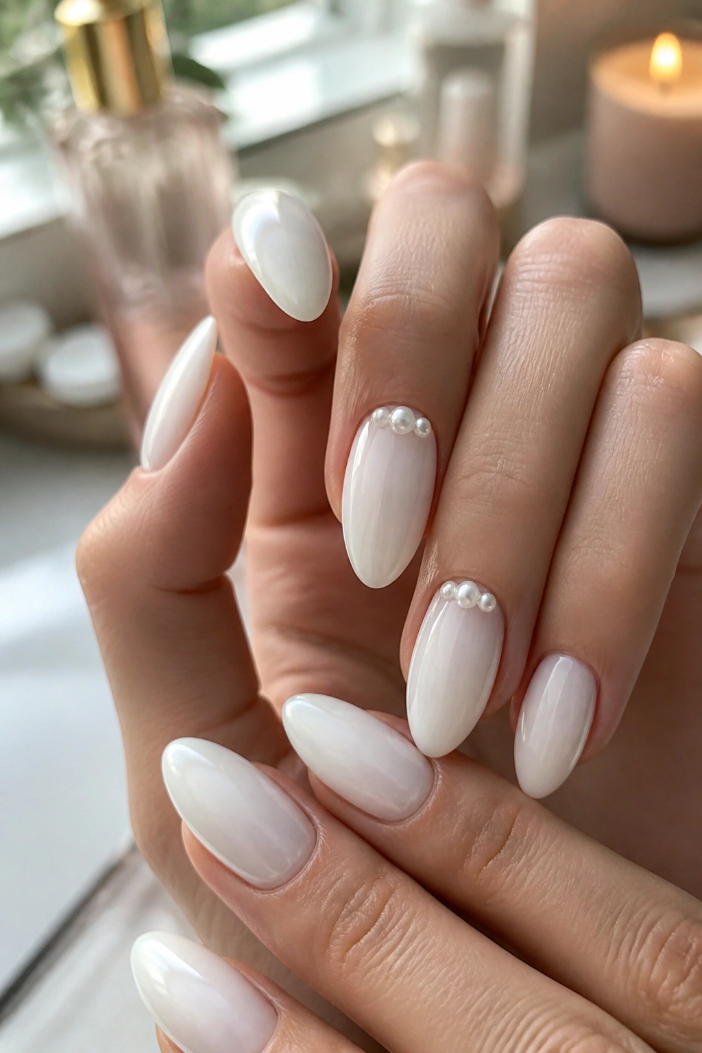Close-up of white almond nails with tiny pearl accents on a real hand