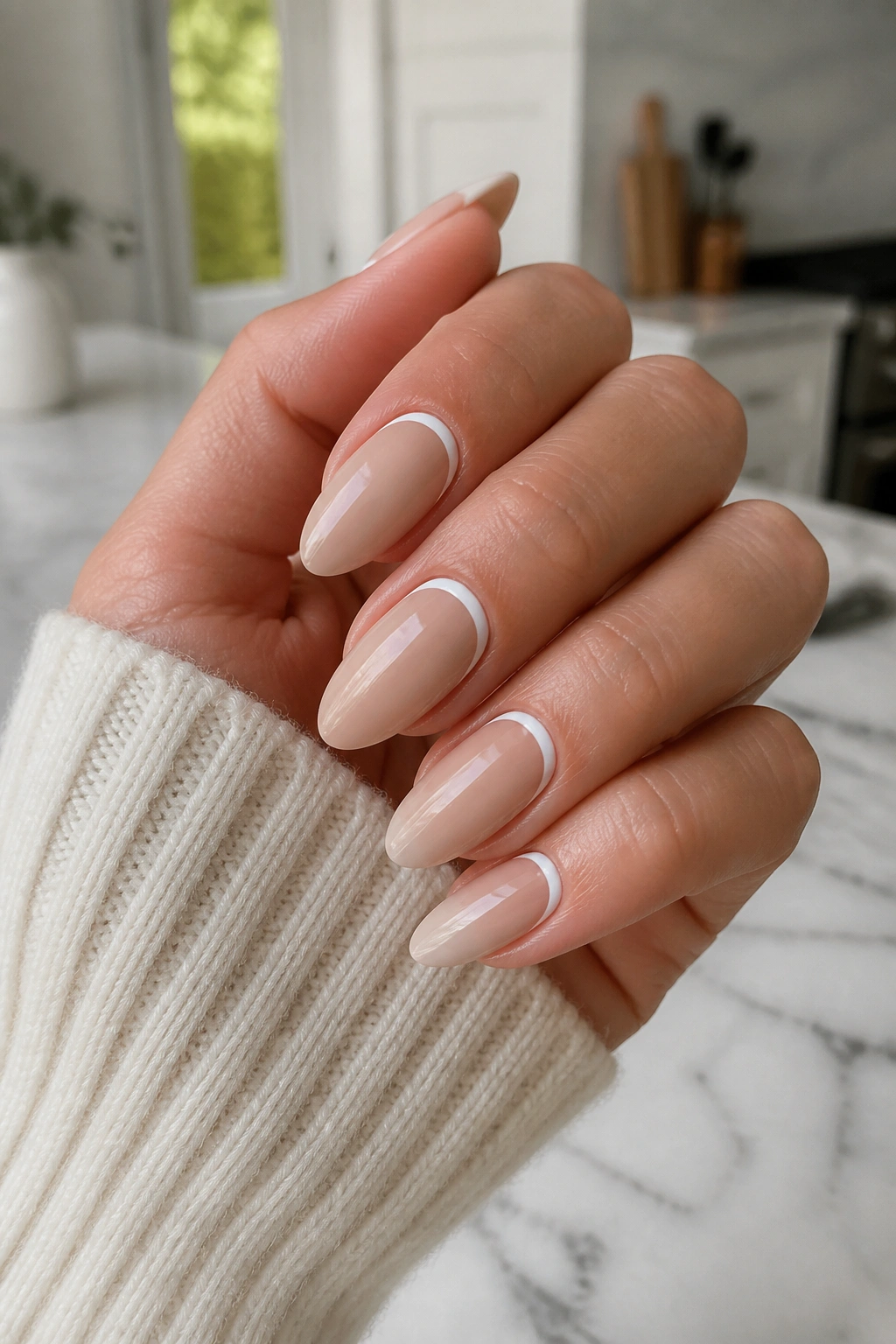Close-up of hand showing white crescent nude almond nails