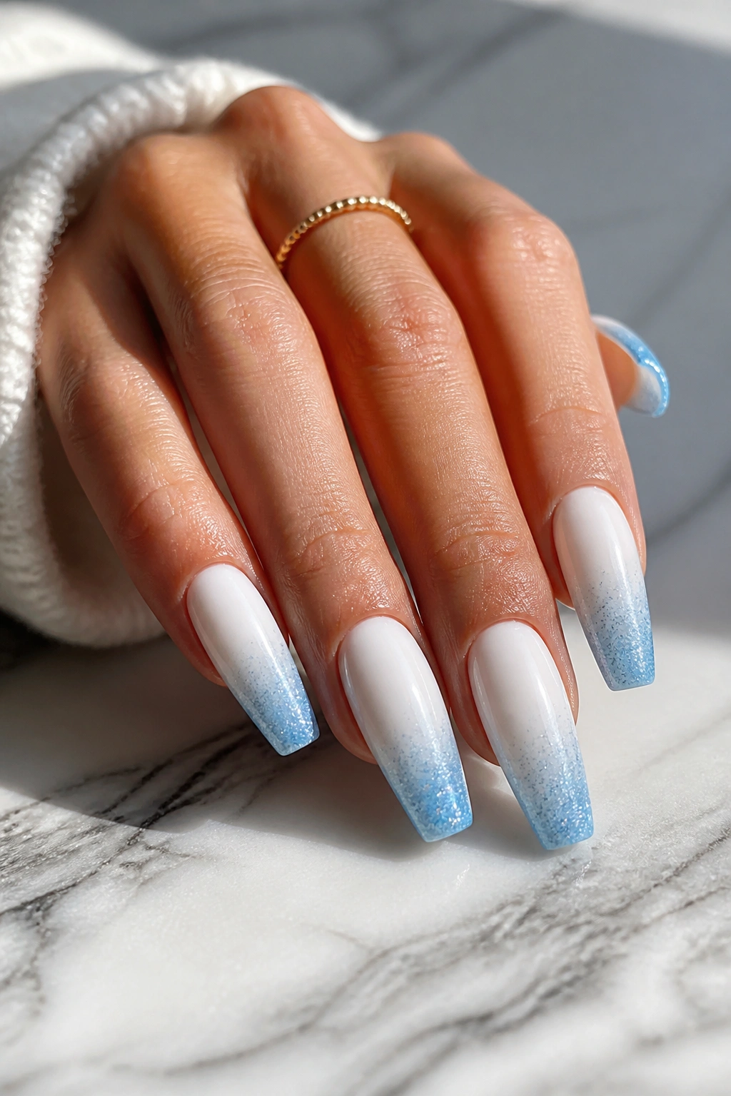 White coffin nails with icy blue glitter fade at tips in natural daylight