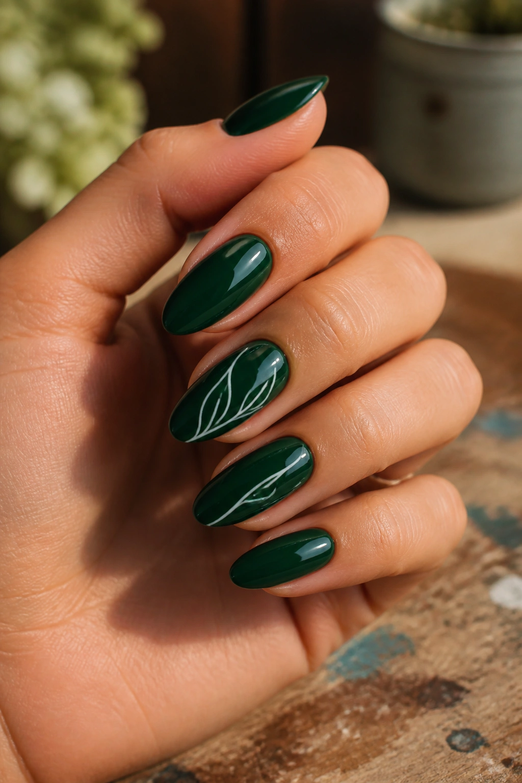 Close-up of deep green almond nails with delicate white line art