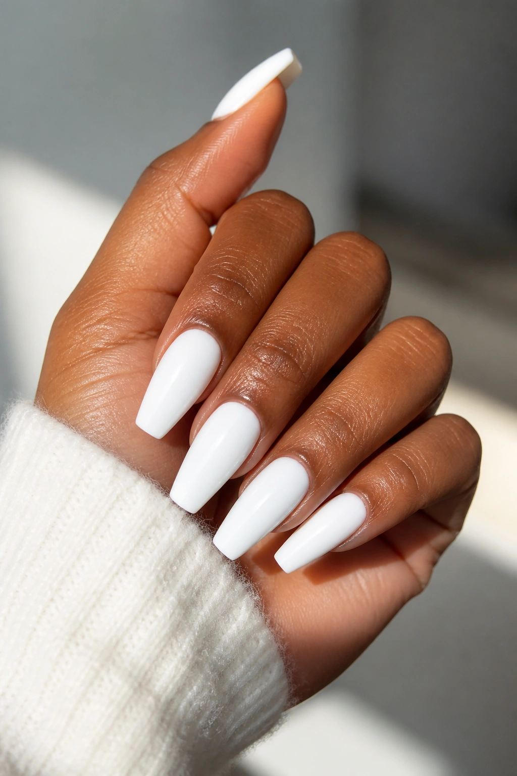 Hand with bright white nails against neutral background