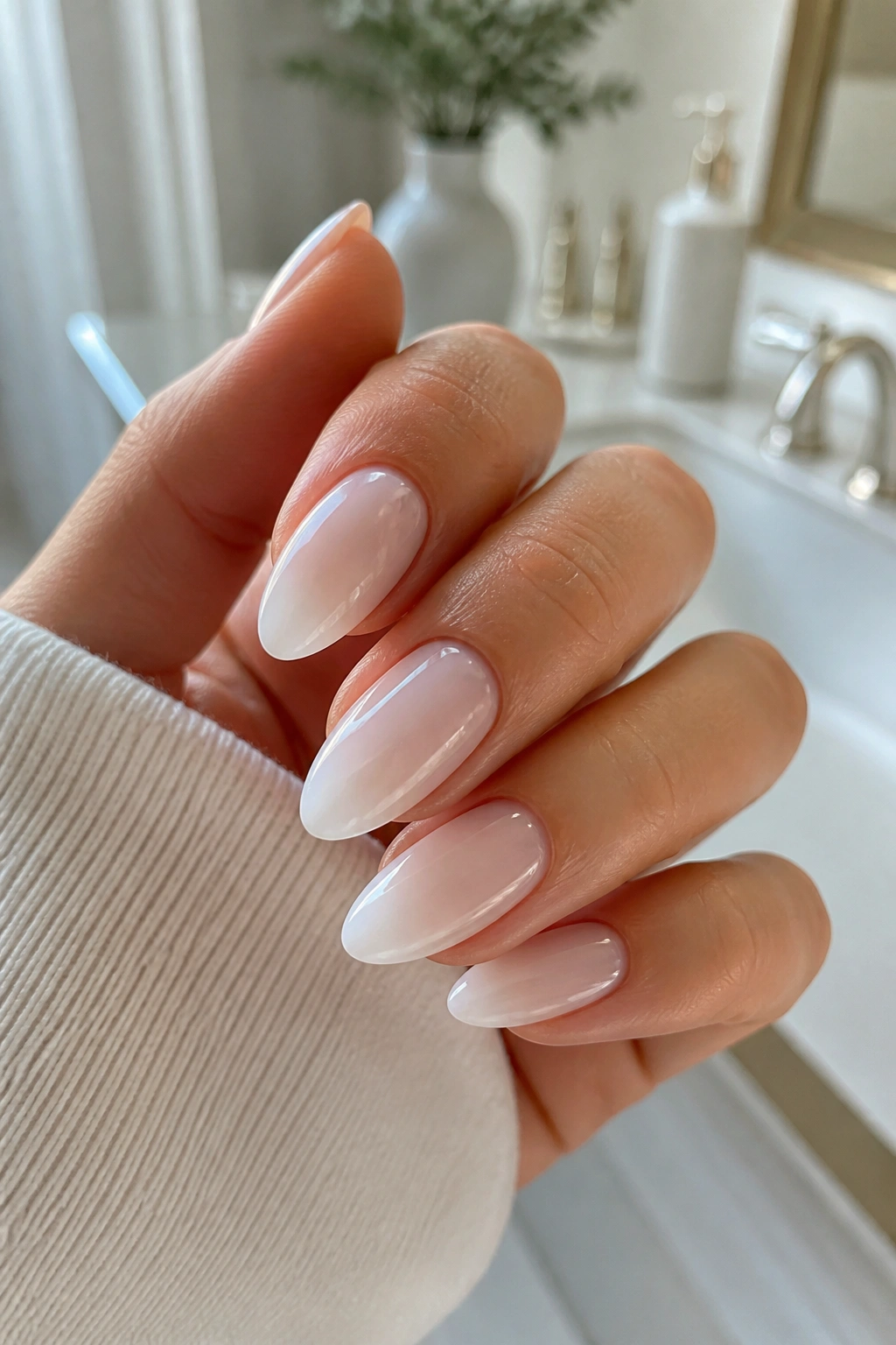 Close-up of white-on-white sheer ombre almond nails on a real hand