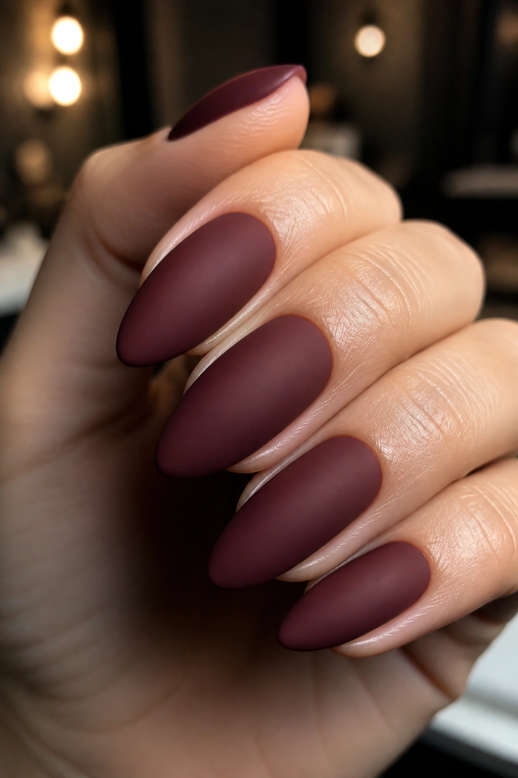 Close-up of matte wine red almond nails on a real hand