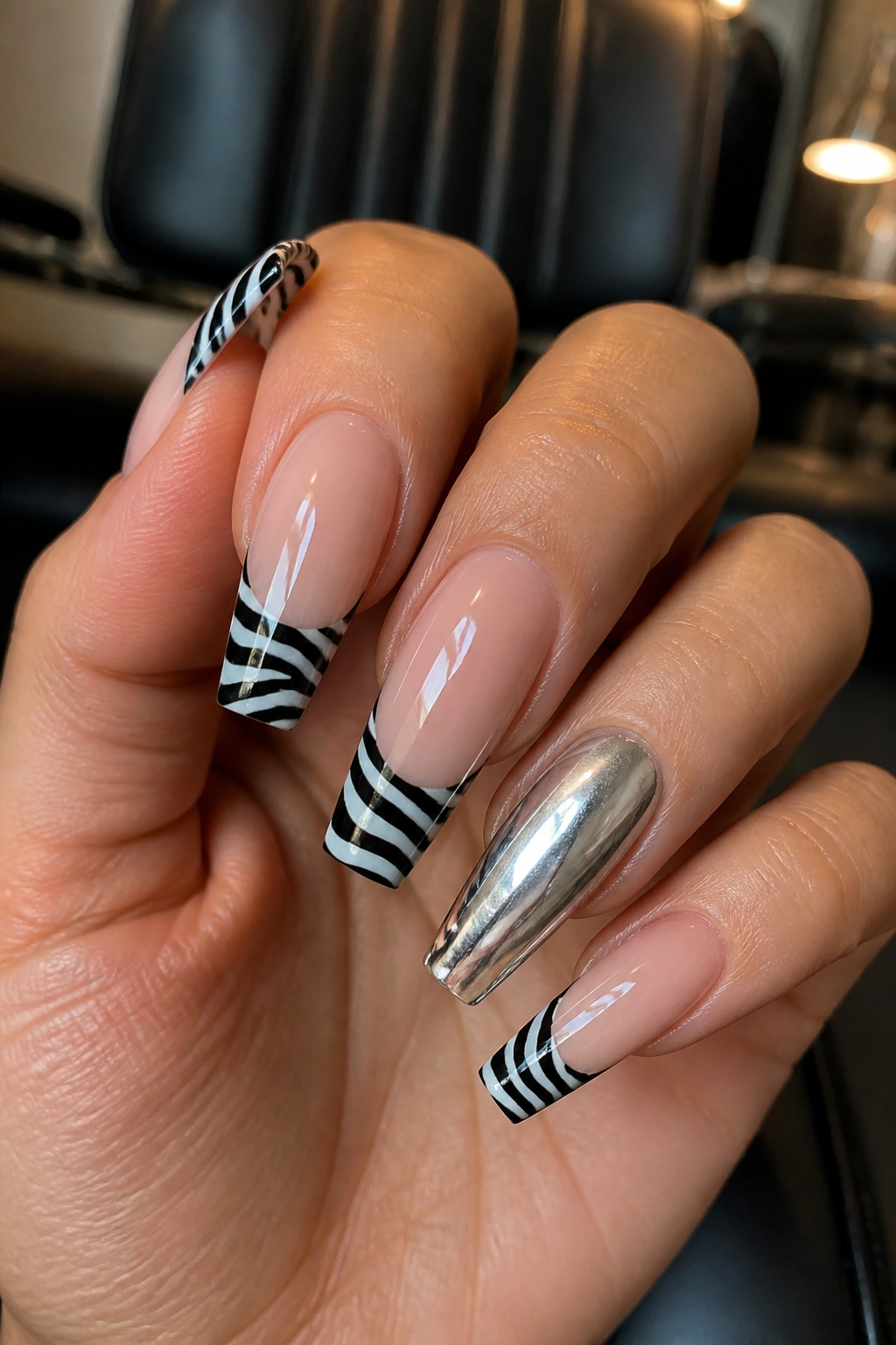 Close-up of zebra print tip nails with a silver accent nail on a real hand